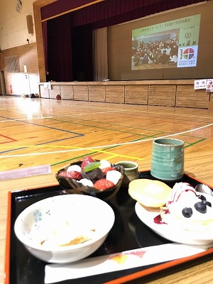 体育館でお盆の上に食事とお茶が乗っている写真